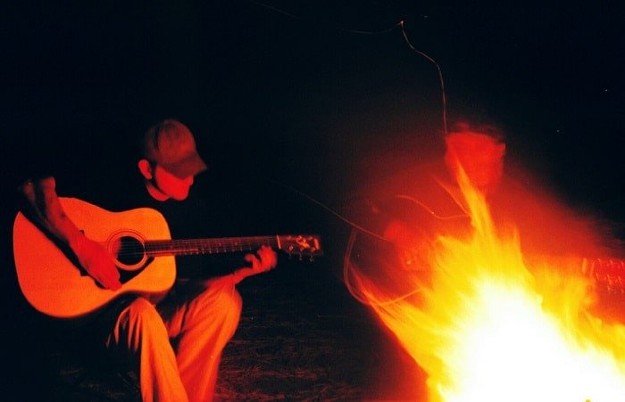 Guy playing guitar in front fire